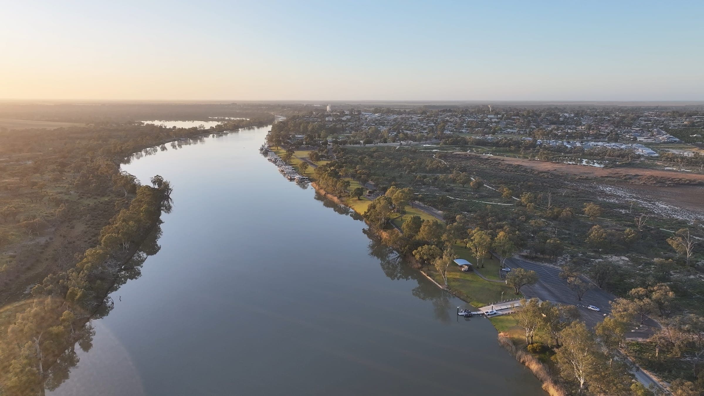 Aerial view of the Murray River winding past a Riverland town in early morning light